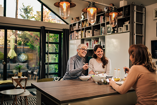 Family dinner. Senior mother and two daughters having meal together at modern home.