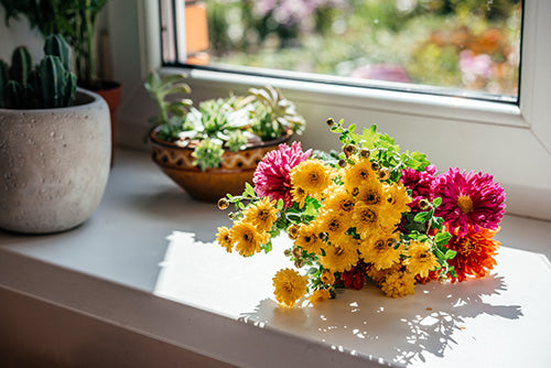 Beautiful autumn bouquet of yellow aster and chrysanthemum flowers on the windowsill